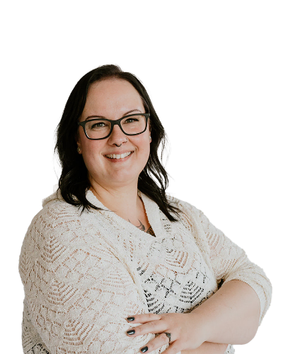 Woman with dark hair and glasses smiles with arms crossed, wearing a white patterned sweater, against a plain white background.