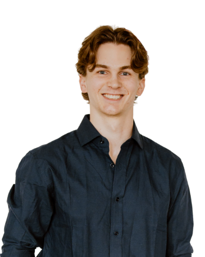 A young man with wavy brown hair wearing a dark button-up shirt, smiling at the camera against a plain white background.