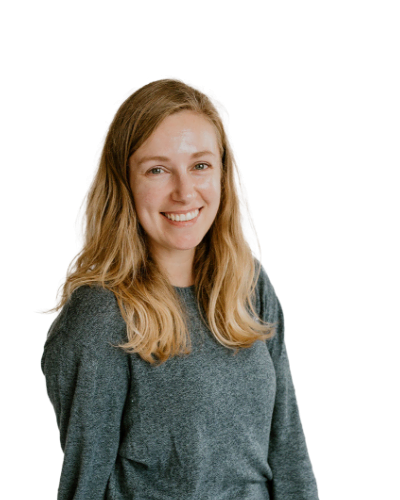 A woman with long blonde hair wearing a gray sweater is smiling at the camera against a plain white background.