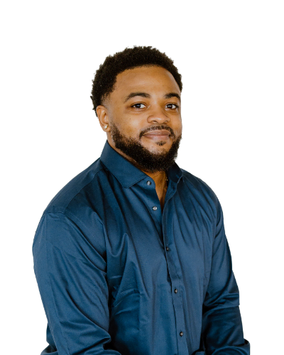 A man with short curly hair and a beard wears a dark blue button-down shirt and smiles slightly, posing against a plain white background.