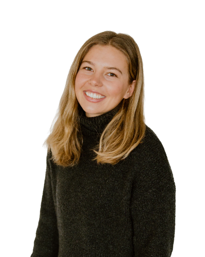 A young woman with straight, shoulder-length blonde hair and a black turtleneck sweater smiles at the camera against a plain white background.