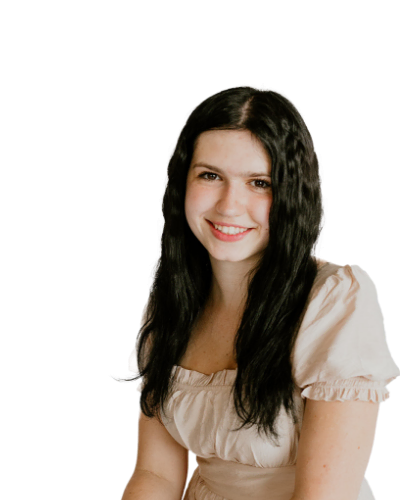 A young woman with long black hair wearing a light beige short-sleeved top sits and smiles at the camera against a plain white background.