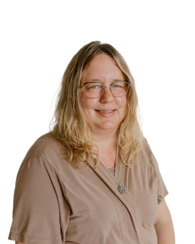 A woman with shoulder-length blonde hair, glasses, and a brown shirt smiles at the camera against a plain white background.