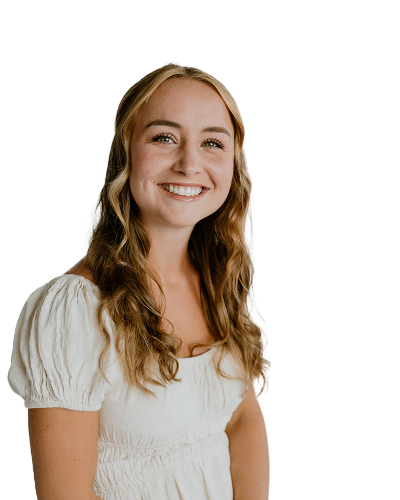 A young woman with long wavy hair, wearing a white short-sleeved blouse, smiles at the camera against a plain white background.