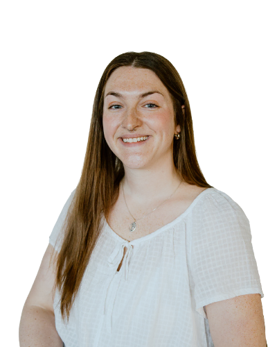 A woman with long brown hair, wearing a white blouse, smiles at the camera against a plain white background.
